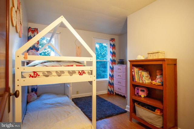 bedroom with vaulted ceiling, baseboards, multiple windows, and wood finished floors