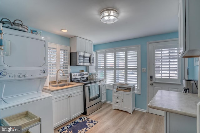 2 E Atlantic St Unit 1, Fenwick Island, DE 19944 - kitchen with stainless steel appliances, estacked washer and dryer, a sink, light wood finished floors, and white cabinets