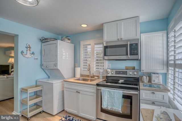 2 E Atlantic St Unit 1, Fenwick Island, DE 19944 - kitchen with stainless steel appliances, stacked washer / dryer, a sink, and light countertops