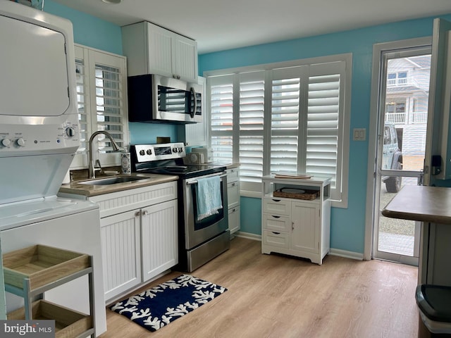 2 E Atlantic St Unit 1, Fenwick Island, DE 19944 - kitchen featuring appliances with stainless steel finishes, stacked washer and clothes dryer, a sink, light wood finished floors, and plenty of natural light