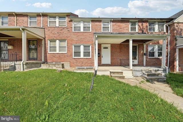 back of property featuring covered porch, a lawn, and brick siding