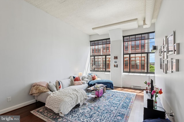 living area featuring a textured ceiling, wood finished floors, and baseboard heating