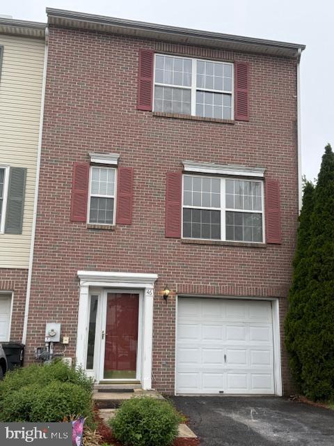 townhome / multi-family property with brick siding, driveway, and a garage