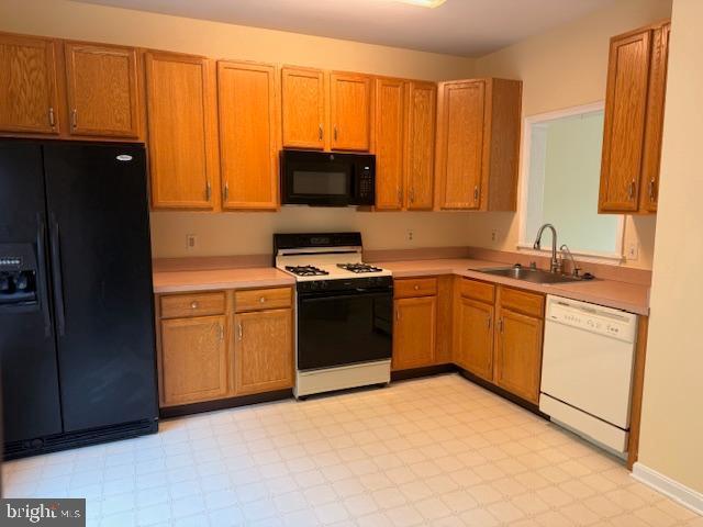 kitchen with black appliances, light countertops, light floors, and a sink