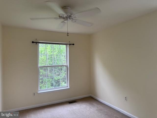carpeted spare room featuring a ceiling fan, a wealth of natural light, and baseboards
