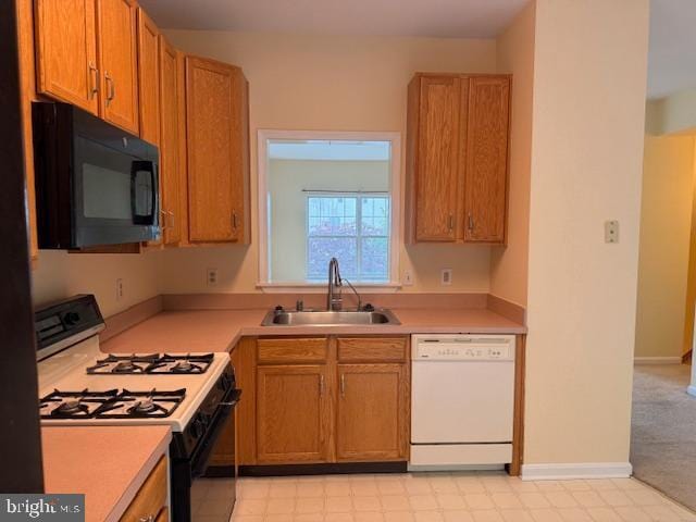 kitchen featuring dishwasher, range with gas stovetop, a sink, black microwave, and light countertops