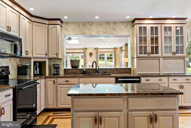 kitchen featuring black appliances, a sink, light wood finished floors, a center island, and recessed lighting