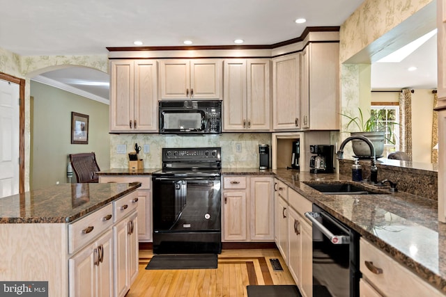 kitchen with black appliances, a sink, arched walkways, ornamental molding, and light wood-style floors