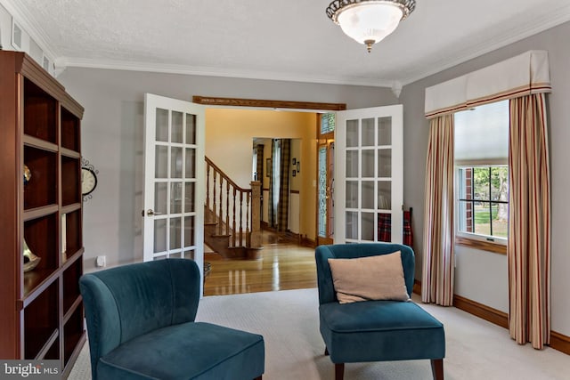 living area featuring french doors, ornamental molding, baseboards, and stairs