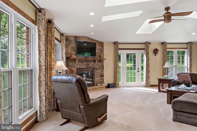 living room with a skylight, a fireplace, carpet floors, vaulted ceiling, and ceiling fan