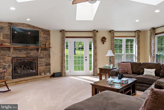 living room with a skylight, carpet flooring, recessed lighting, and a stone fireplace