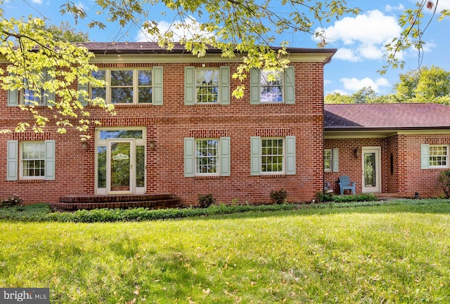 back of property with brick siding and a yard