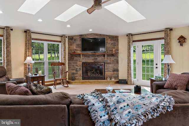 living area featuring a skylight, a stone fireplace, recessed lighting, and lofted ceiling