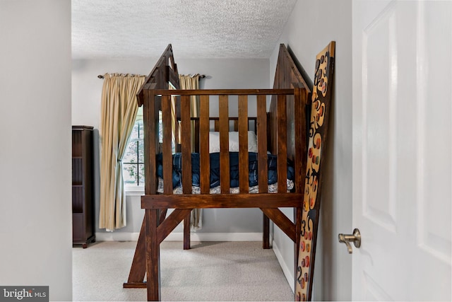 stairway with a textured ceiling, carpet floors, and baseboards