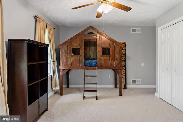 carpeted bedroom featuring a textured ceiling, a closet, baseboards, and a ceiling fan