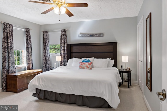 carpeted bedroom with a textured ceiling, baseboards, and ceiling fan