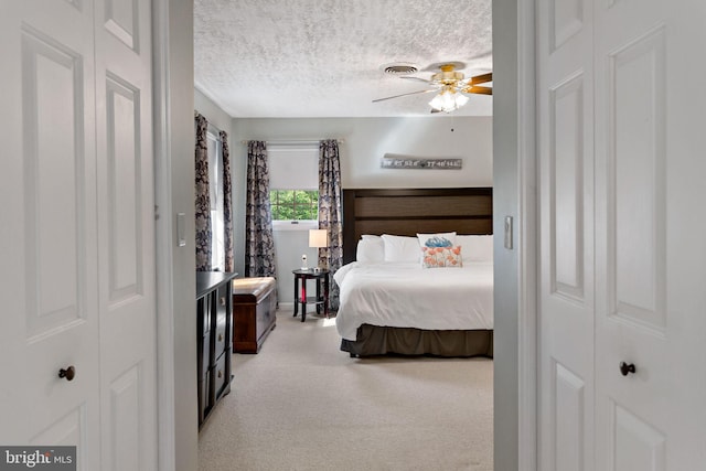 bedroom with light carpet, a textured ceiling, and ceiling fan
