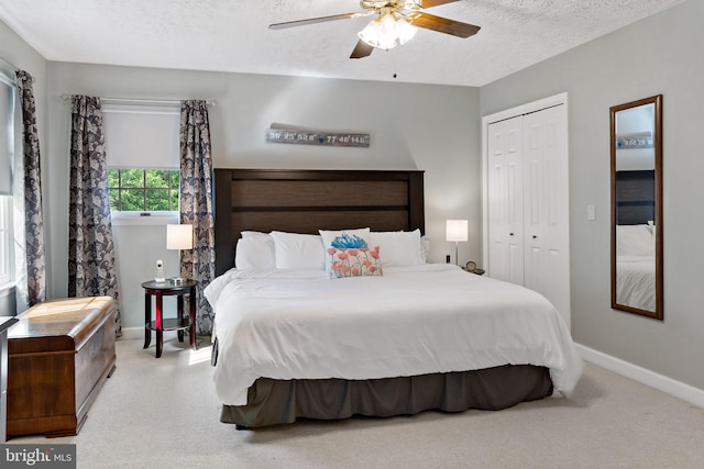carpeted bedroom with baseboards, a closet, a textured ceiling, and ceiling fan