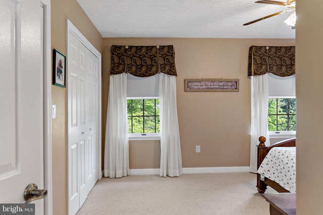 bedroom featuring carpet flooring, baseboards, a closet, a ceiling fan, and a textured ceiling