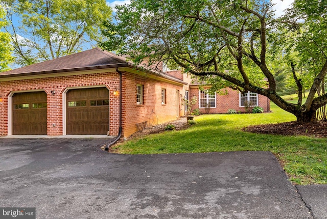 view of home's exterior featuring brick siding, a garage, a yard, a shingled roof, and asphalt driveway