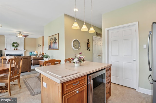 kitchen with beverage cooler, freestanding refrigerator, ceiling fan, pendant lighting, and light countertops