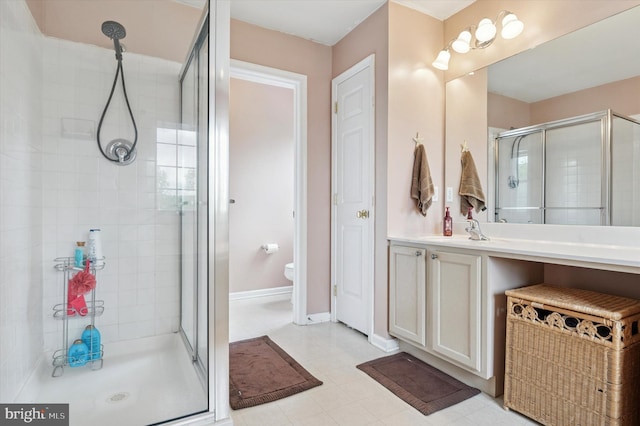 bathroom with a stall shower, vanity, toilet, and baseboards