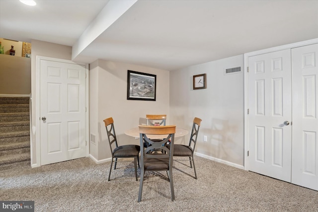 dining area featuring carpet, baseboards, and stairs