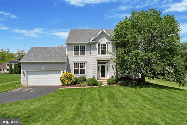 view of front of home with asphalt driveway, a front lawn, and an attached garage