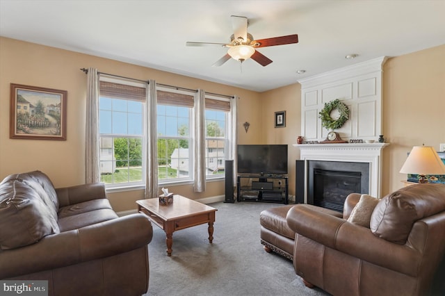 carpeted living room featuring a ceiling fan, healthy amount of natural light, a glass covered fireplace, and baseboards