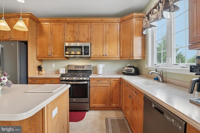 kitchen featuring stainless steel appliances, a sink, light countertops, and hanging light fixtures