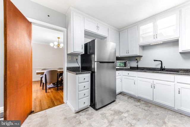 1417 Glendale Rd, Baltimore, MD 21239 - kitchen featuring freestanding refrigerator, a sink, white cabinets, a chandelier, and dark stone counters