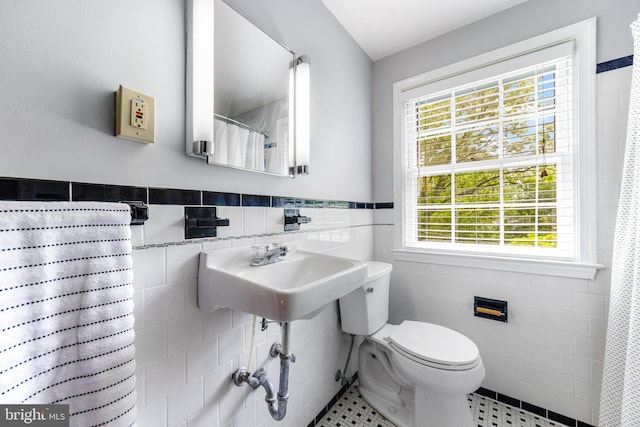 1417 Glendale Rd, Baltimore, MD 21239 - full bathroom featuring tile walls, plenty of natural light, toilet, tile patterned flooring, and wainscoting
