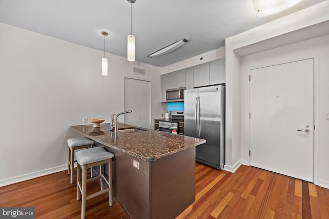 2101 Market St Unit 705, Philadelphia, PA 19103 - kitchen featuring a sink, a peninsula, gray cabinets, wood finished floors, and appliances with stainless steel finishes