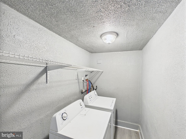 laundry area with wood finished floors, laundry area, a textured ceiling, a textured wall, and independent washer and dryer