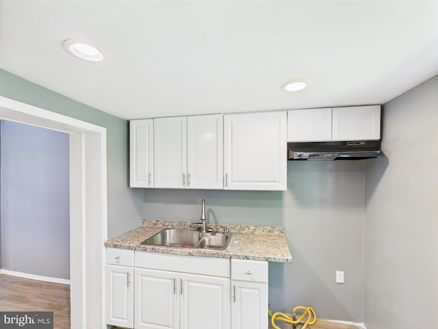 kitchen with under cabinet range hood, white cabinetry, a sink, and light countertops