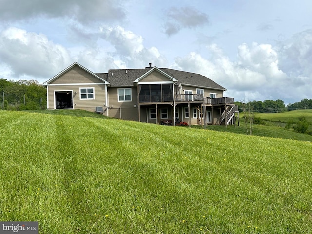 rear view of house with a yard, a deck, a sunroom, and central AC unit