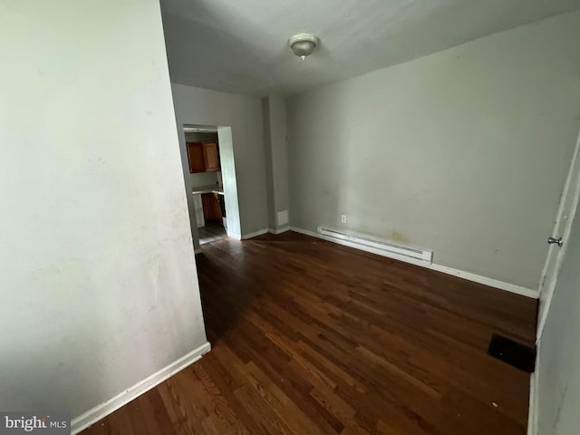 spare room with baseboards, a baseboard radiator, and dark wood finished floors
