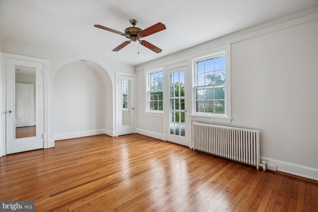 1362 Sheridan St NW, Washington, DC 20011 - spare room featuring radiator heating unit, hardwood / wood-style floors, ceiling fan, and arched walkways