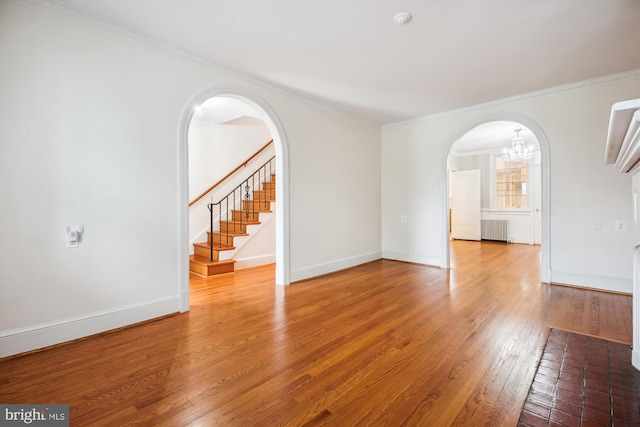 1362 Sheridan St NW, Washington, DC 20011 - spare room with radiator heating unit, arched walkways, a chandelier, crown molding, and wood finished floors