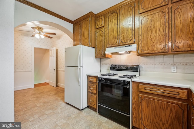 1362 Sheridan St NW, Washington, DC 20011 - kitchen with gas range, under cabinet range hood, freestanding refrigerator, a ceiling fan, and brown cabinets