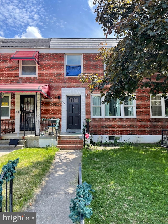 townhome / multi-family property with a front lawn and brick siding
