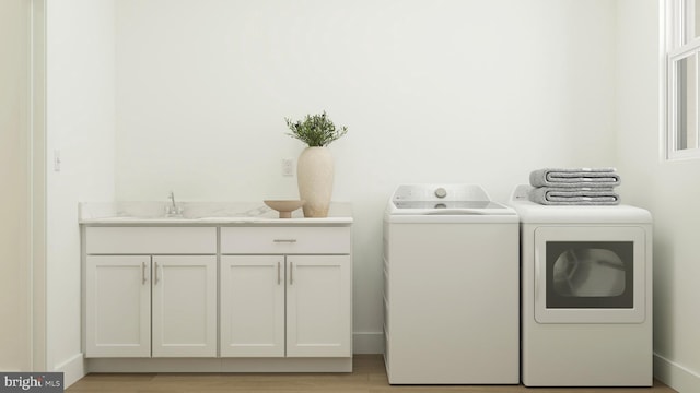laundry room featuring light wood finished floors, cabinet space, a sink, and washer and clothes dryer