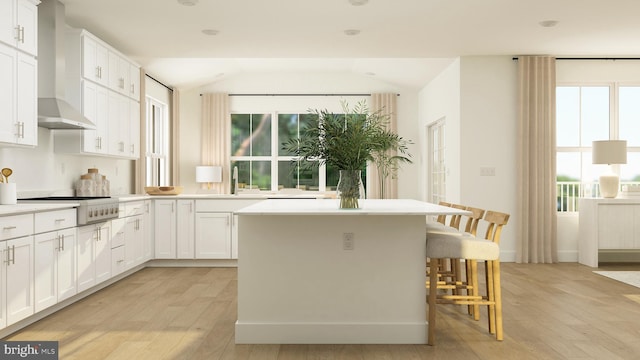 kitchen featuring a breakfast bar area, cooktop, white cabinetry, a kitchen island, and light wood-style floors