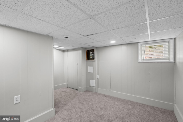 below grade area with carpet flooring, a drop ceiling, and baseboards