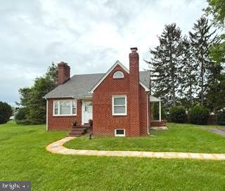 view of front facade with a front lawn, brick siding, and a chimney
