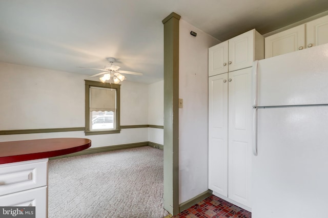 kitchen with freestanding refrigerator, ceiling fan, white cabinetry, baseboards, and brick patterned floors
