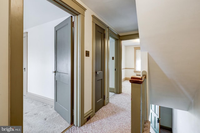 hallway featuring carpet flooring and baseboards