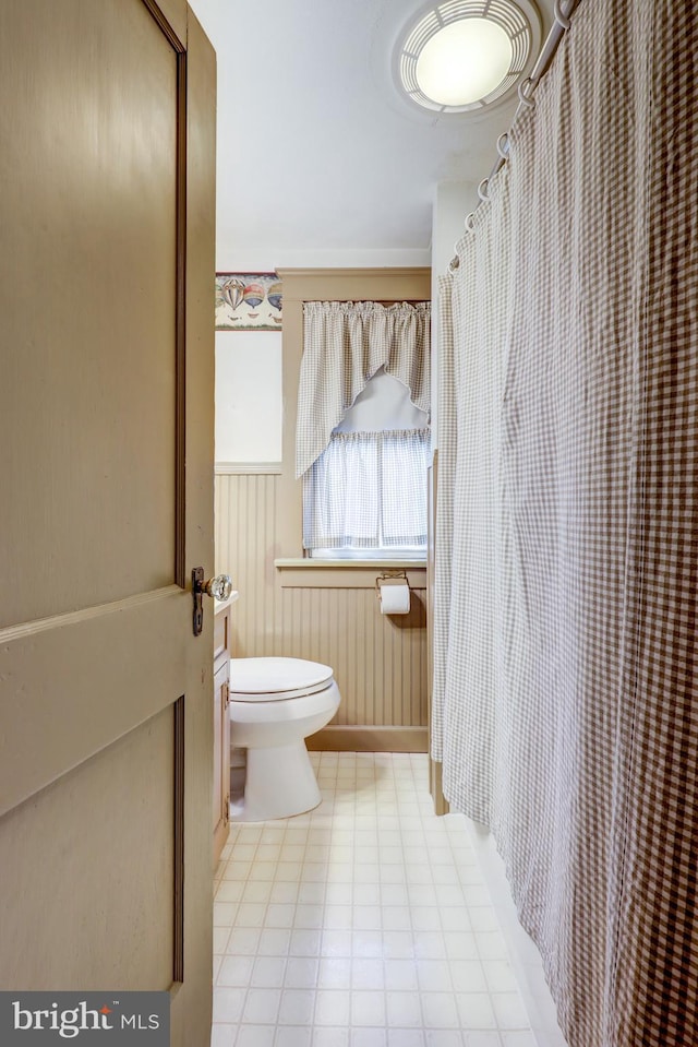 bathroom with toilet, baseboards, and curtained shower