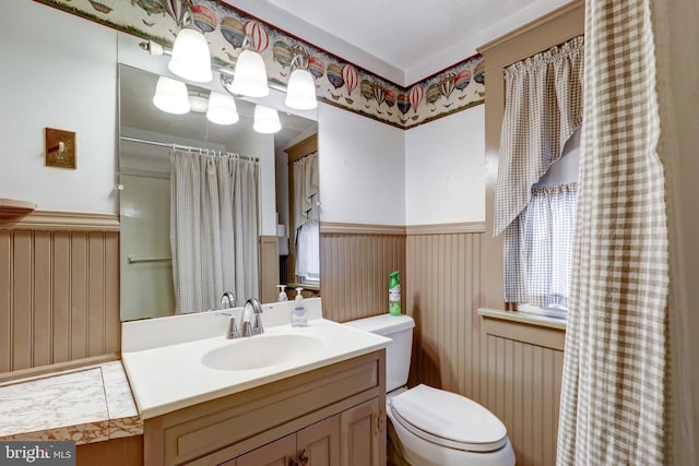 full bathroom with a wainscoted wall, toilet, vanity, and a shower with shower curtain