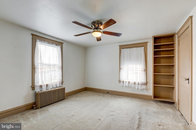 unfurnished bedroom featuring radiator, carpet, baseboards, and ceiling fan